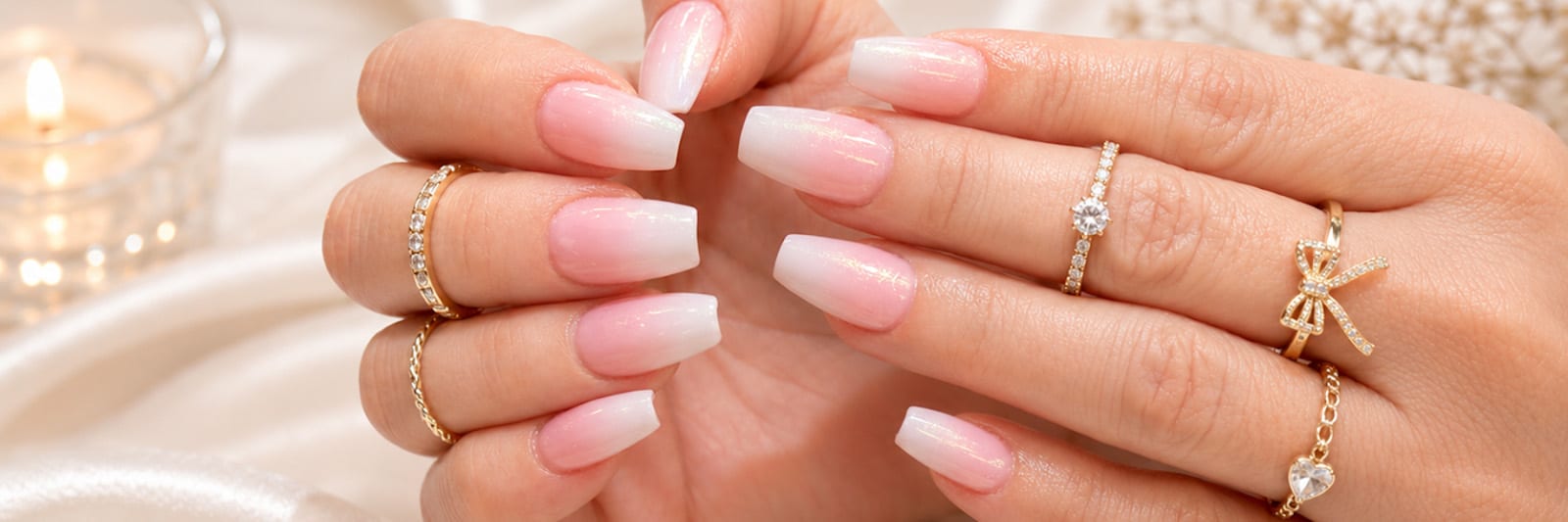 Close-up of an ombre manicure with jewelry against a satin background
