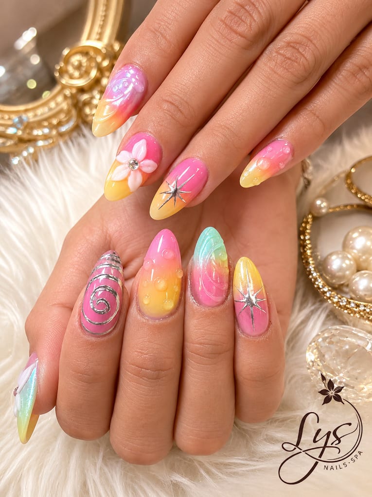 Pink, yellow, and teal ombre nails with 3D floral and starburst accents