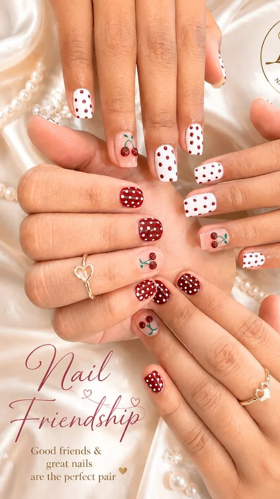 Red and white polka dot nails with hand-painted cherry accents