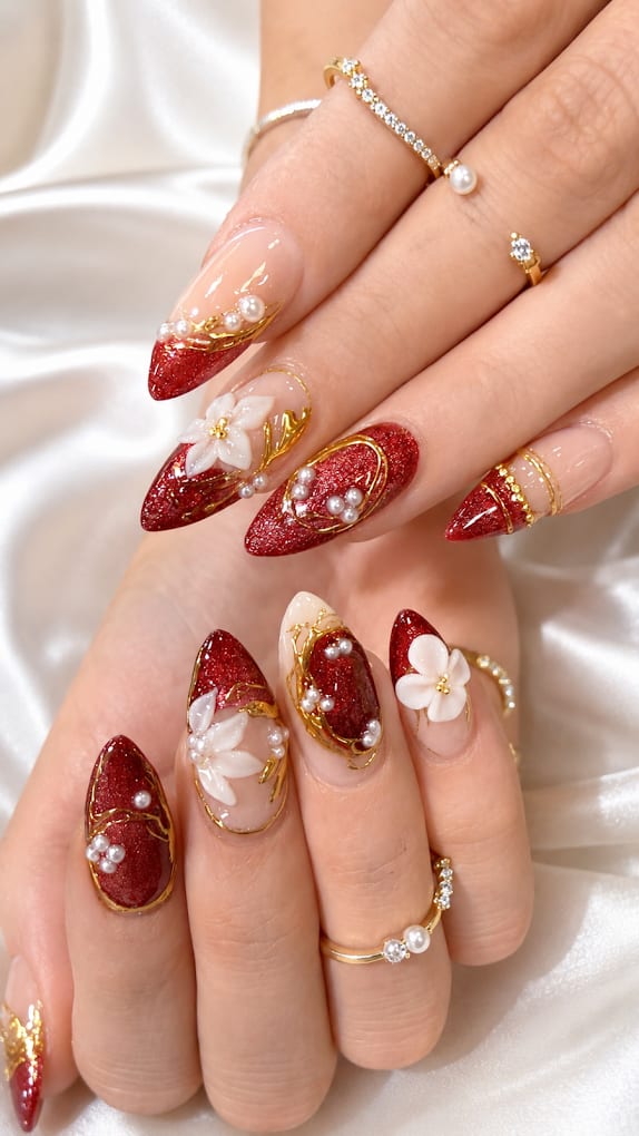 Deep red glitter almond nails with 3D white floral and gold pearl accents