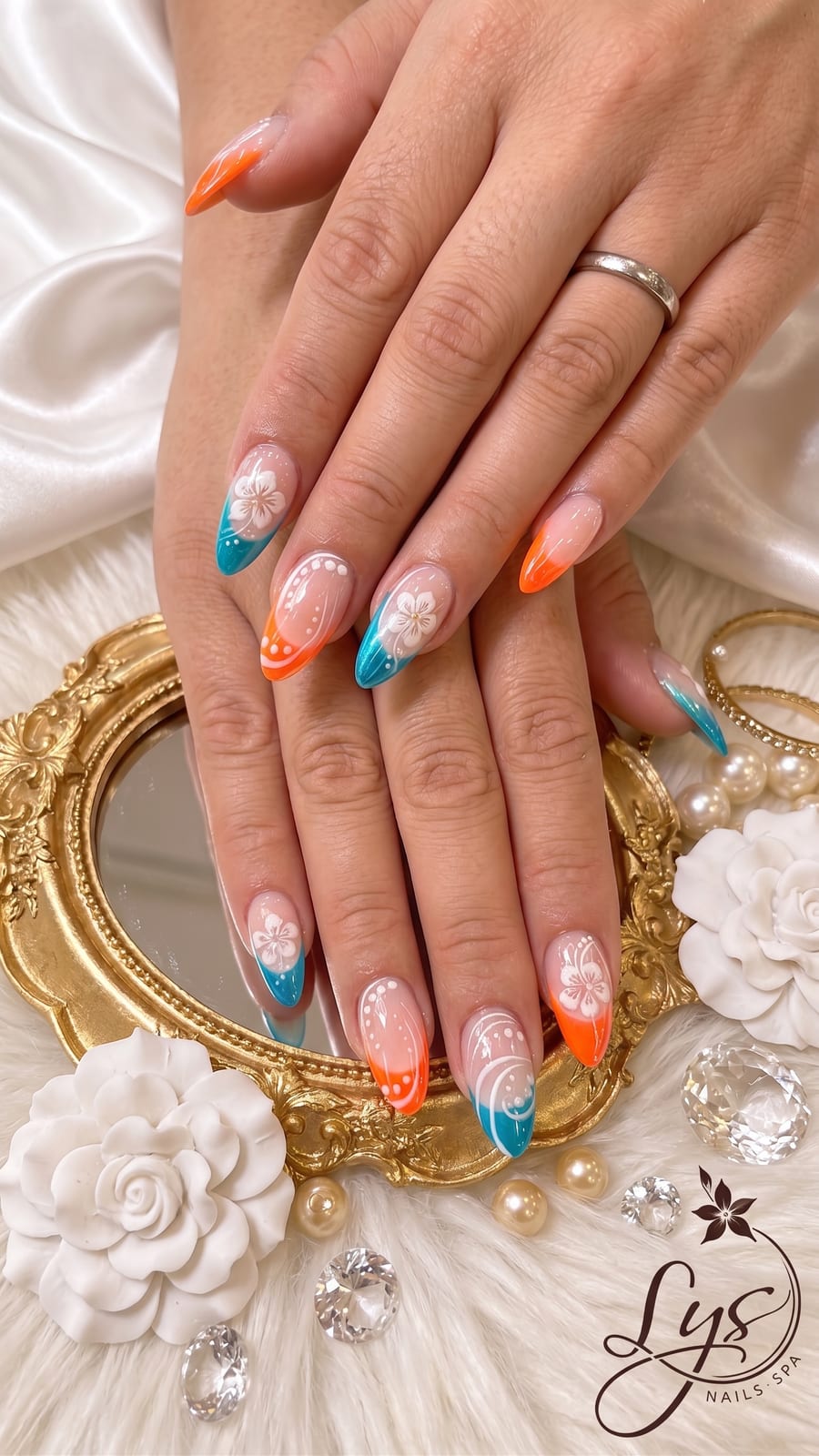 Orange and teal ombre French tip nails with white floral art