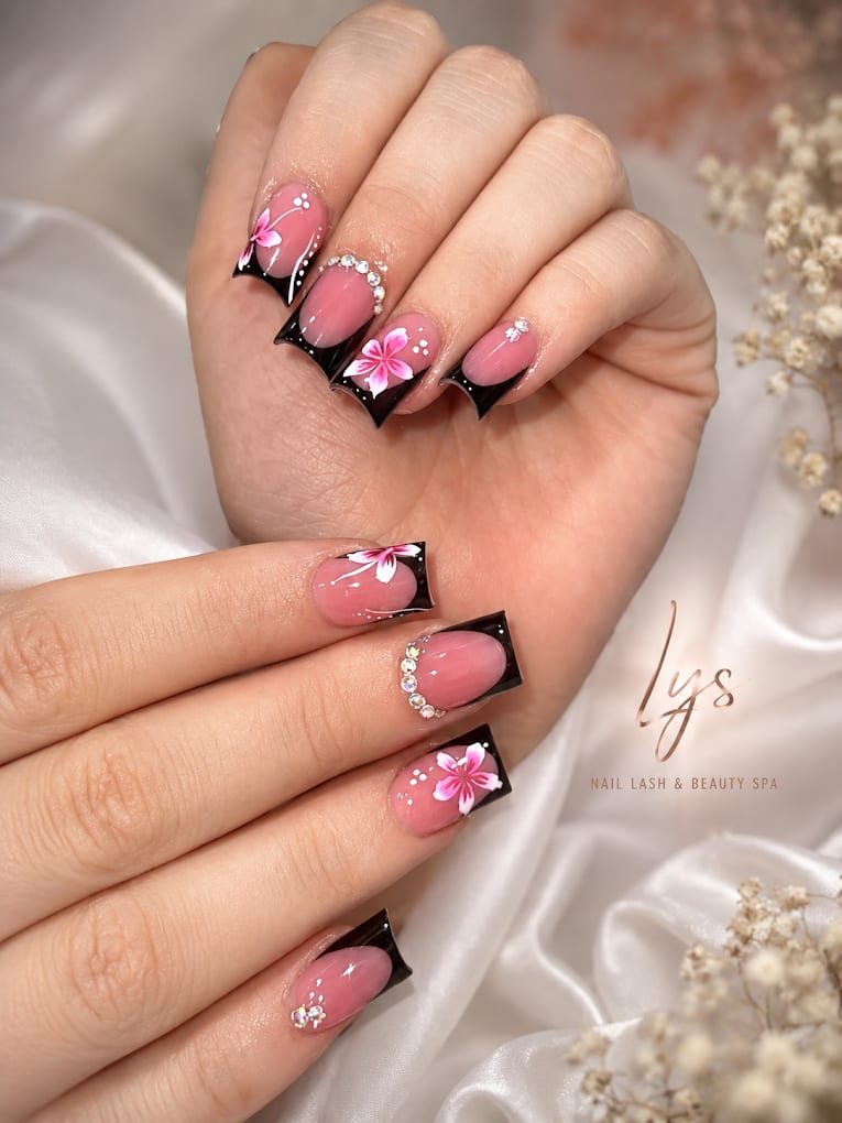 Pink and black nail art with floral details and rhinestone accents